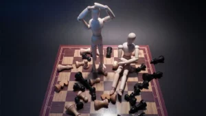 Deux pantins de bois sur un échiquier semblant décontenancés à cause de toutes les pièces d'échecs retournées
